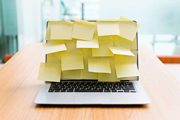 Viele Post-It-Zettel auf Notebook symbolisieren ironisch strukturierte Kommunikation mit Teams-Chat und E-Mail